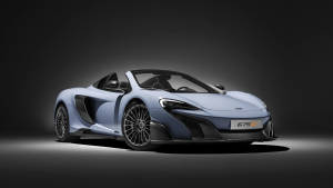 淺藍色McLaren 675LT跑車，帶有黑色飾件和銀色輪圈，在深灰色工作室背景上。