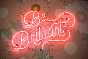 在花卉牆紙背景下寫著「Be Brilliant」的霓虹燈牌。 — 型格動態圖 壁紙