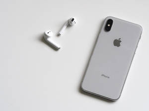 銀色 iPhone X 和白色 AirPods 在白色表面上。
