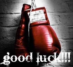 紅色拳擊手套掛在磚牆上，帶有「good luck!!!」塗鴉。
