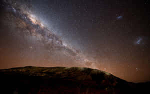 銀河系在星空下拱起於黑暗的山影之上。