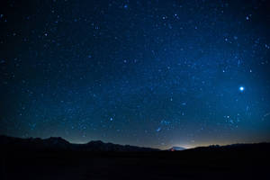 黑暗的山巒在繁星點點的夜空下，一顆明亮的行星清晰可見。 — 星星 壁紙