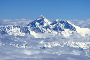 白雪覆蓋的山峰聳立在厚厚的雲層之上。 — 雲朵 壁紙