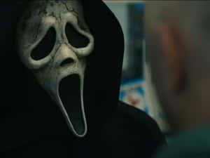 Ghostface面具在昏暗場景中面向一個人。
