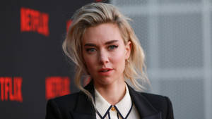 金髮女性在Netflix活動中身穿黑色西裝外套和白色襯衫。
