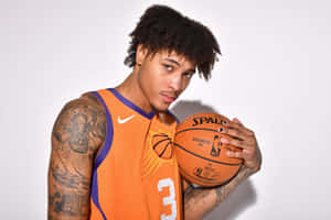 身穿橙色球衣的籃球運動員手持 Spalding 籃球，紋身可見。 — 籃球 壁紙