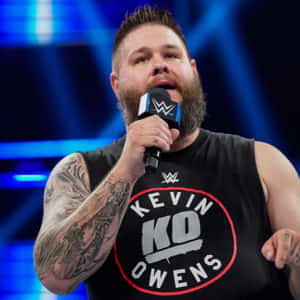 WWE摔角手Kevin Owens在舞台上對著咪高峰說話。 — 1:1 壁紙