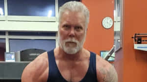 一位肌肉發達的白鬍鬚老年男子在健身房穿著背心