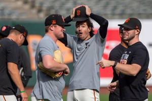 棒球運動員在陽光明媚的球場上穿著巨人隊裝備慶祝。