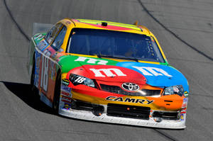 M&M's豐田Camry賽車在日落時分的陽光賽道上疾馳。 — 汽車 壁紙