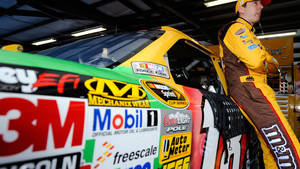 NASCAR車手在車庫內靠在帶有贊助商貼紙的賽車上。 — 汽車 壁紙
