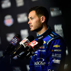 NASCAR車手在記者會上穿著帶有贊助商標誌的藍色賽車服。