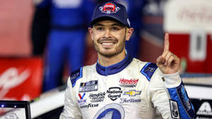 NASCAR車手高舉獎盃並微笑向上指