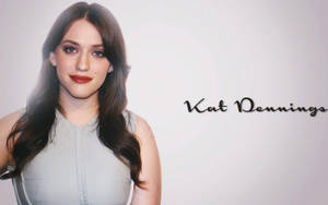Kat Dennings 着住灰色連衣裙，留住長長嘅棕色頭髮同紅色唇膏。