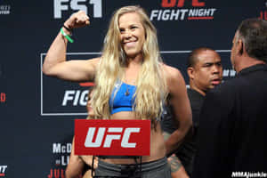女MMA拳手在UFC稱重活動中彎曲二頭肌。