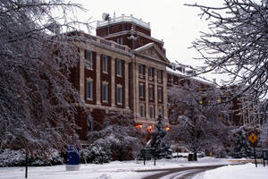 被雪覆蓋的大學建築，帶有霜凍的樹木和一條寧靜的小路。
