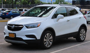 白天在城市停車場停泊的白色 Buick Encore SUV。
