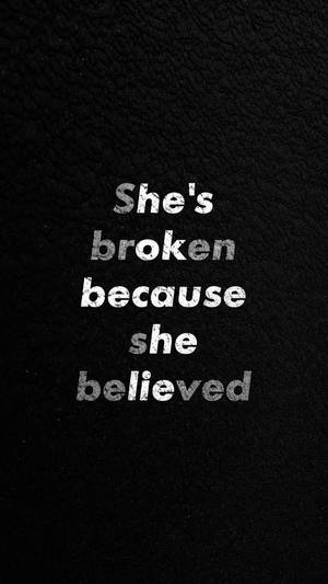 黑色皮革背景上的文字引用顯示「She's broken because she believed」 — 語錄 壁紙