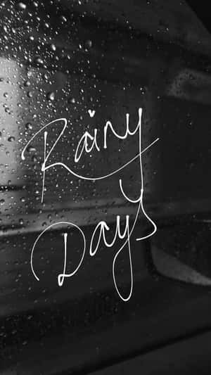 喺濕咗嘅車窗上用白色草書寫嘅Rainy Days。