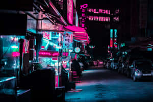 夜晚街道，發光的霓虹招牌和停泊的汽車映照在潮濕的路面上。 — 夜晚 GIF 壁紙