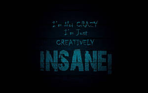 深色木材上的藍色塗鴉風格文字寫著「I'm Not Crazy I'm Just Creatively Insane!」。 — 窩心語錄 壁紙