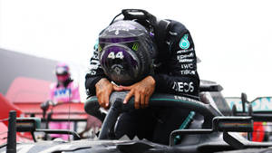 F1車手在比賽後將頭靠在方向盤上的手臂上休息。 — 黑色動態圖 壁紙