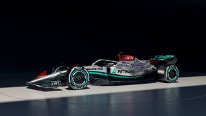 一輛帶有Petronas品牌的銀色和藍綠色一級方程式賽車，在工作室燈光下。