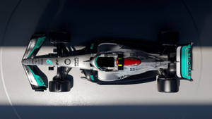 從上方俯瞰一輛帶有 Petronas 贊助的 Formula 1 賽車在混凝土表面上。