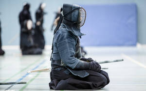 全副武裝的劍士在道場中手持竹劍跪地。 — 戰士 壁紙