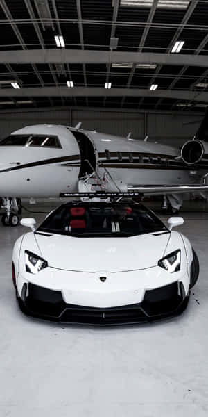 白色林寶堅尼 Aventador 停放在機庫內的私人飛機旁邊。 — 18:9 壁紙