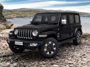 黑色Jeep Wrangler Unlimited停在水邊的岩石海灘上