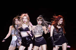 K-pop 組合在舞台上穿著閃亮服裝，擺出動感姿勢表演。