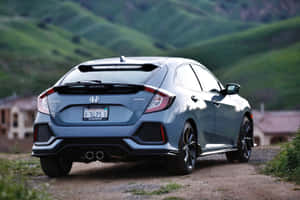 藍色本田Civic Sport停泊在泥路上，後面有綠色山丘。
