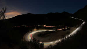 夜晚蜿蜒的山路，在星空下帶有發光的汽車軌跡。