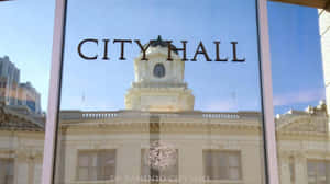 市政廳大樓倒映在寫有「city hall」的玻璃窗上。