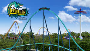 加拿大奇幻樂園的 Leviathan 過山車，在晴朗的天空下，周圍有樹木和其他遊樂設施。 — 過山車 壁紙