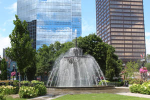 城市公園中的噴泉，周圍有高樓大廈和綠樹