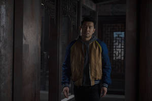 穿外套的男人站在有格子窗的傳統木製走廊中。