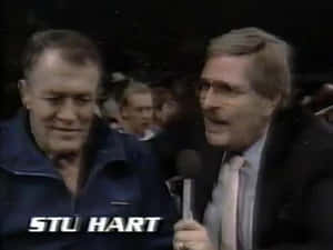 摔角手 Stu Hart 在擠滿人的競技場中接受記者訪問。
