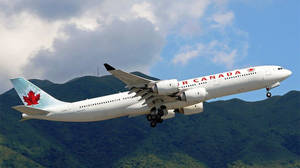 加拿大航空飛機在藍天白雲下，降落在綠色山脈之上。