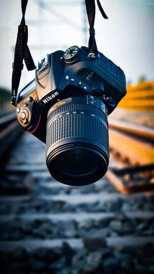 黑色 Nikon DSLR 相機在日光下懸掛在鐵路軌道上。