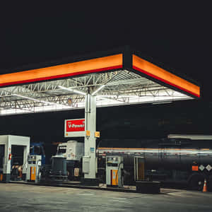 夜間加油站，卡車在明亮的橙色和白色燈光下加油。