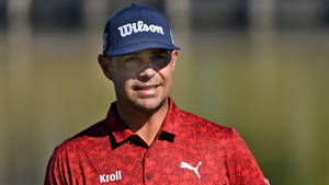 身穿紅色襯衫和藍色帽的高爾夫球手在戶外微笑。 — 運動 壁紙