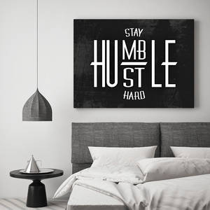現代臥室，灰色床上方有勵志牆飾，寫著「Stay Humble Hustle Hard」。
