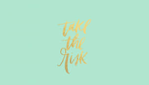 勵志短語 take the risk 以金色閃粉字體寫在薄荷綠色上。