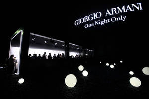 夜間活動，發光球體與Giorgio Armani標誌剪影。
