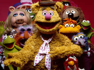 一群開心的Muppet角色一起擺姿勢，帶著燦爛的笑容。