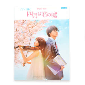 年輕女子演奏小提琴和穿西裝的男孩在櫻花下。