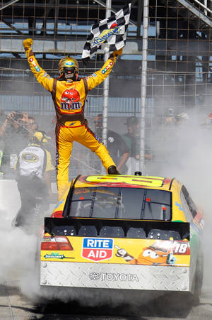 賽車手站在冒煙的車上揮舞格子旗慶祝勝利