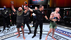 UFC拳手在八角籠中贏得比賽，裁判舉起他的手。